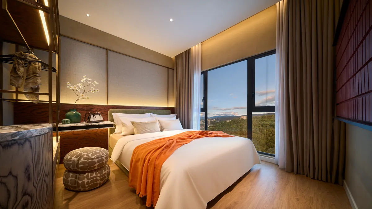 Type A bedroom, warm oak and an orange throw, the window looking out over the hills