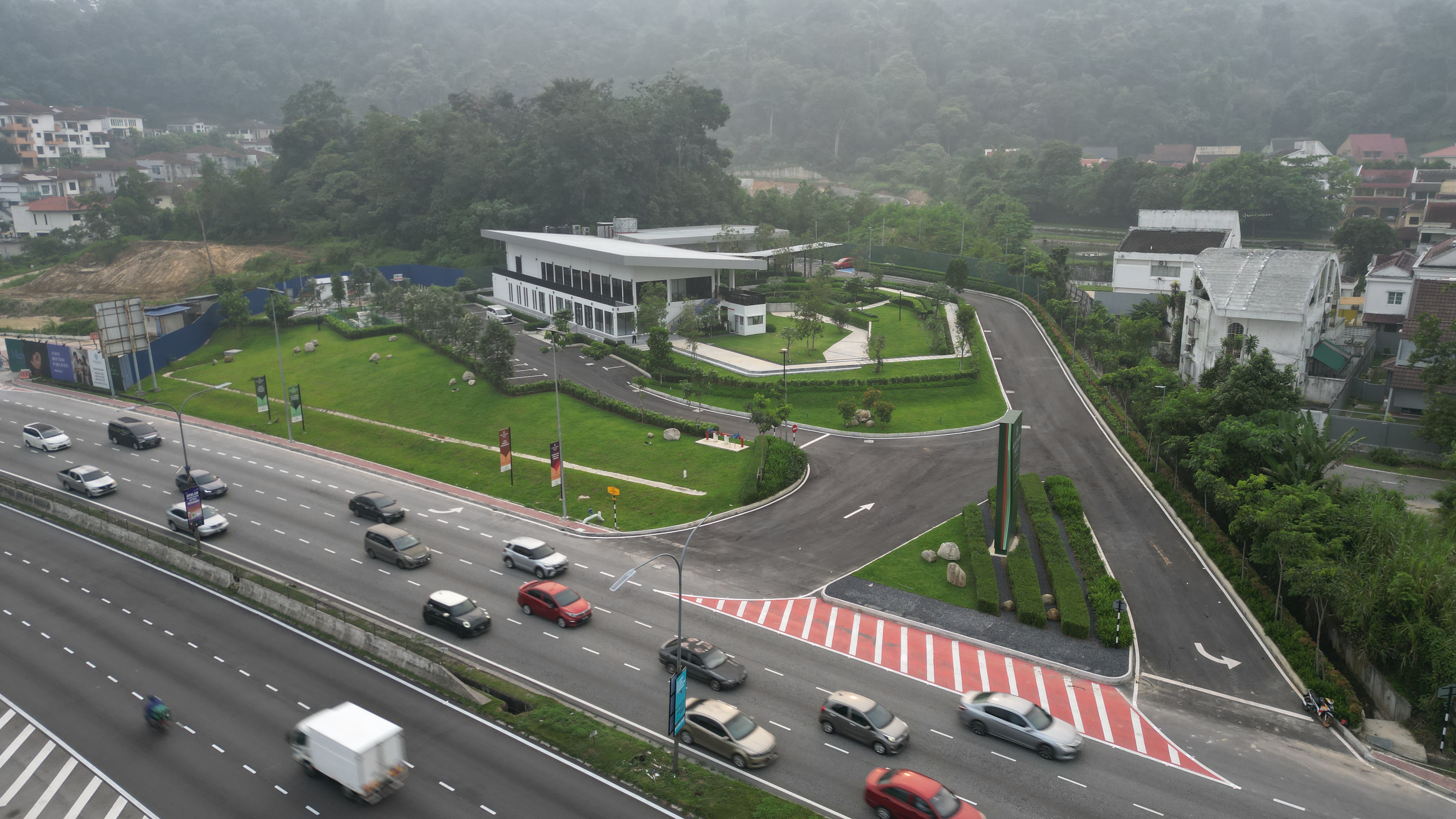 The Merdu sales gallery in daylight, seen from above with the surrounding grounds and highway